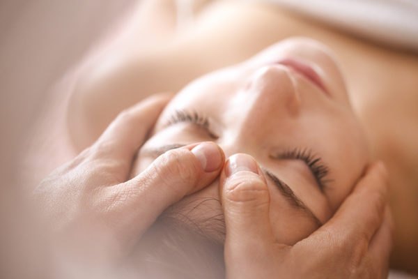 Young woman at a health spa having a head massage. About 20 years old, Caucasian brunette.